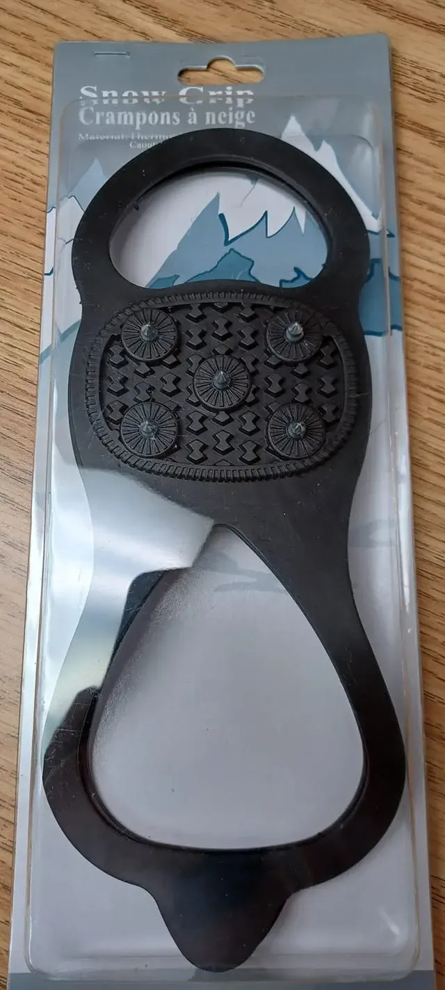 Paire de crampons à neige noirs encore dans son emballage de carton et plastique.