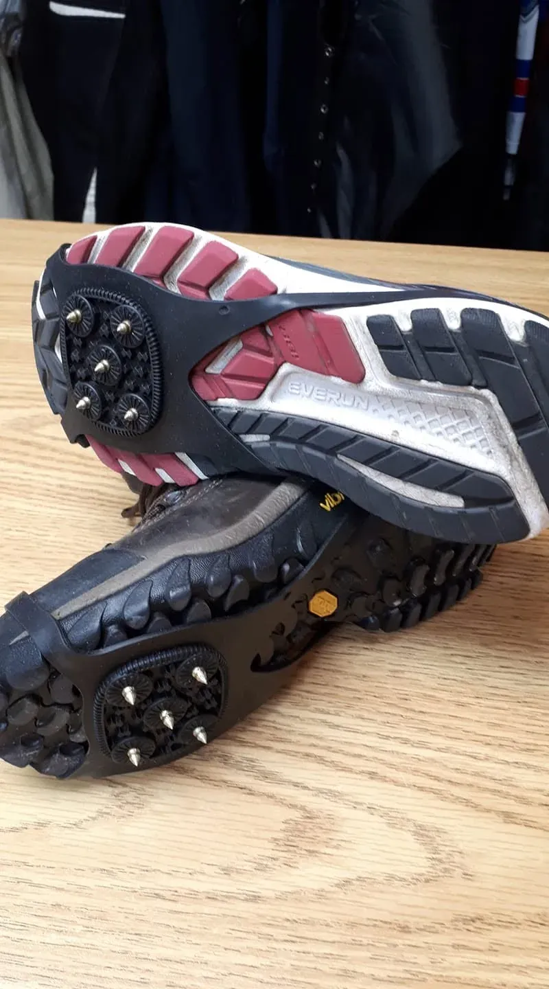 Deux paires de chaussures posées semelles vers le haut, chacune munie de crampons à pointes de métal.